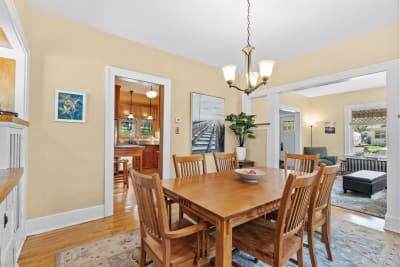 Dining room featuring a wooden table, chairs, a chandelier, and a view of a kitchen.