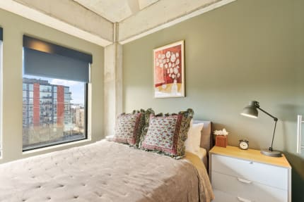 Modern bedroom with olive green walls, a plush bed, and decorative elements.