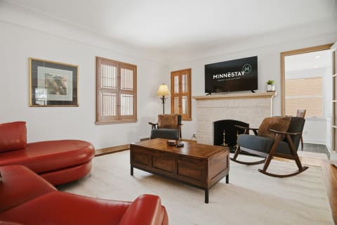 Cozy living room featuring a red leather sectional, wooden coffee table, fireplace, and modern amenities.