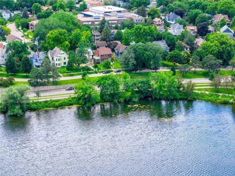 Aerial view of a scenic lakefront neighborhood with tree-lined streets and various residential styles.