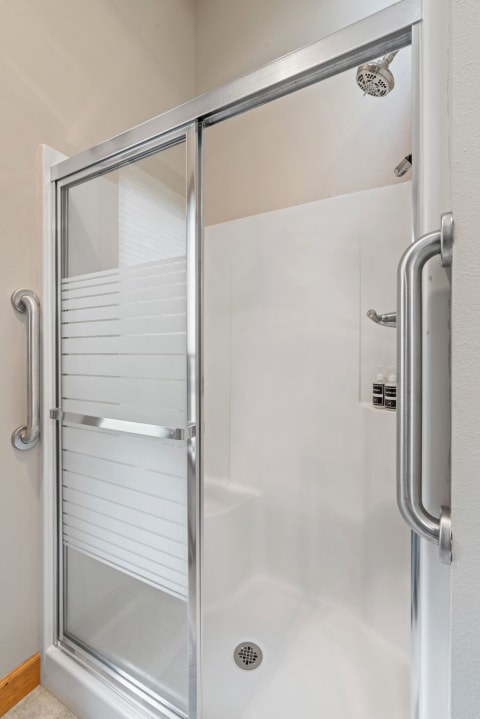 A bright and clean modern shower stall with clear glass sliding doors and white interior.