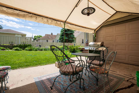 Outdoor seating area with a table, chairs, grill, and backyard view.
