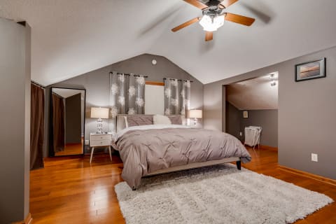 Cozy bedroom with a bed, wooden flooring, and decorative curtains.
