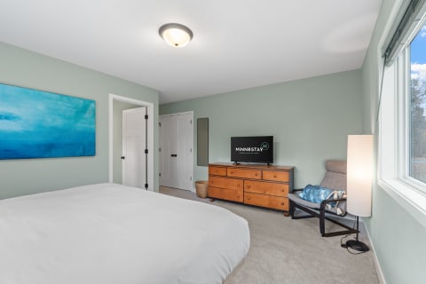 Cozy bedroom featuring light green walls, a large bed, and wooden furniture.