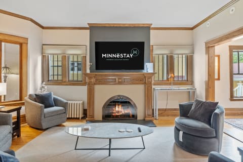 A stylish living room with a fireplace, TV above it, and comfortable seating.