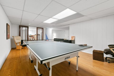 Basement recreation room featuring a ping pong table and cozy seating areas.