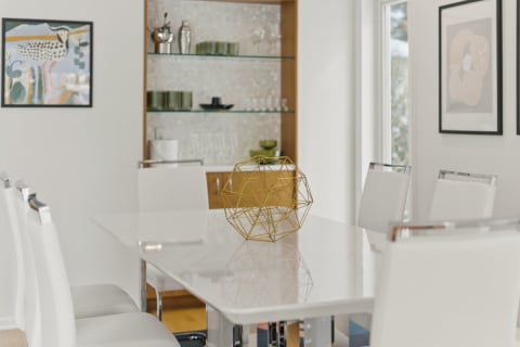 Contemporary dining room with a white table, artistic gold sculpture, and stylish chairs.