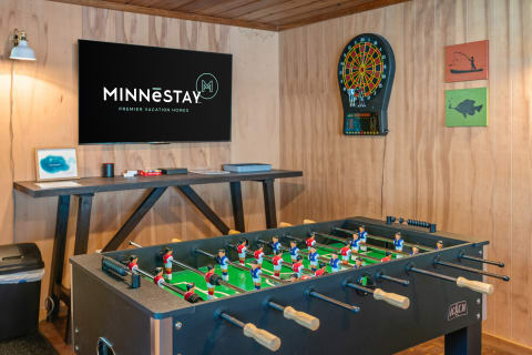 Interior of a recreational room featuring a foosball table, TV, and dartboard.