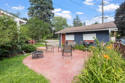 Outdoor patio with chairs, a fire pit, and colorful flowers.