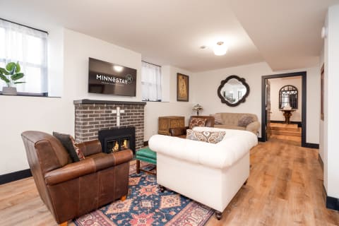 Inviting living room with a tufted white sofa, brown leather chair, fireplace, and modern TV.