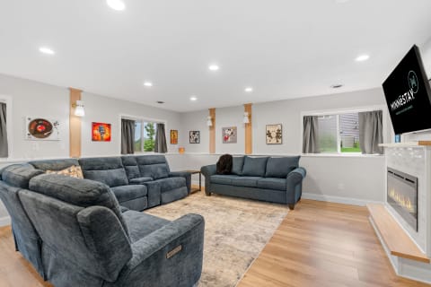 Spacious living room featuring blue sofas, wall art, and an electric fireplace.