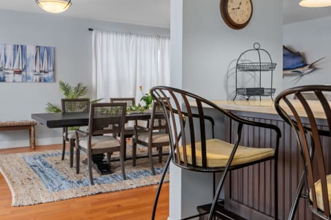 Modern dining area with a table, chairs, a rustic bench, and nautical artwork.