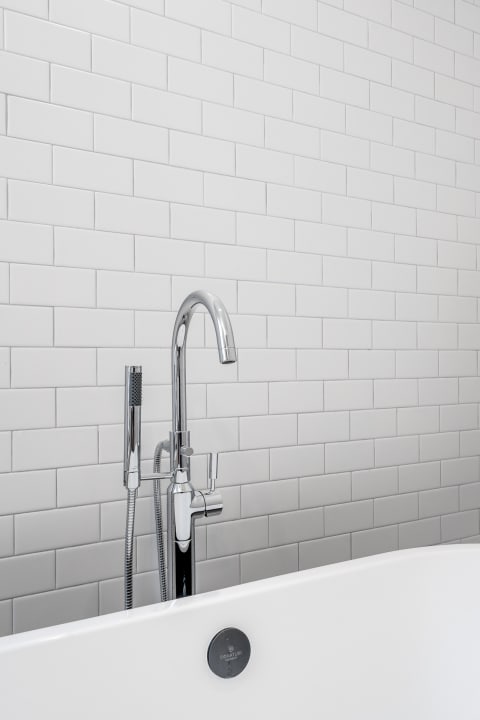 Close-up of a modern chrome faucet and white subway tiles in a bathroom.
