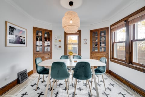 Cozy dining room with a round table, teal chairs, and woven pendant light.