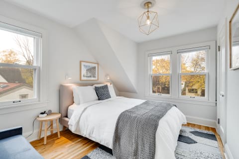 Cozy bedroom featuring a sloped ceiling, large windows, and elegant bed linens.