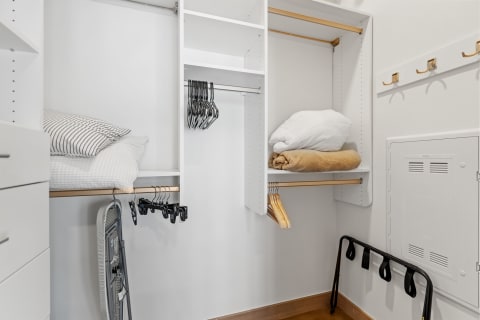 A modern closet featuring neatly stacked bedding and hangers.