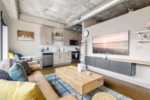 Modern loft apartment with a leather sofa, coffee table, and contemporary kitchen.