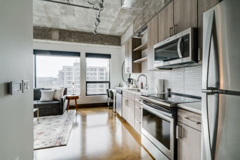 A stylish kitchen and living area featuring stainless steel appliances and large windows.
