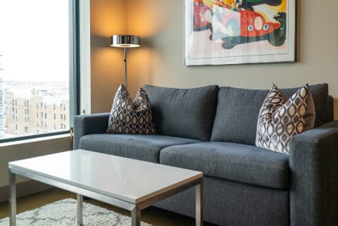 Cozy living room featuring a gray sofa, decorative cushions, and a modern lamp.