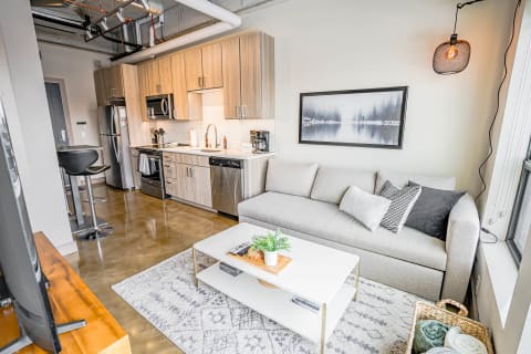 Modern studio apartment featuring a kitchen and comfortable seating area with a coffee table.