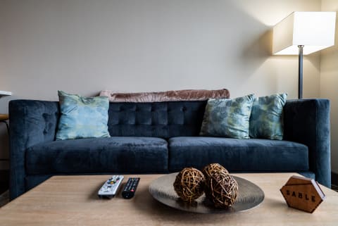Modern living room with a dark blue velvet sofa, decorative pillows, and a cozy atmosphere.