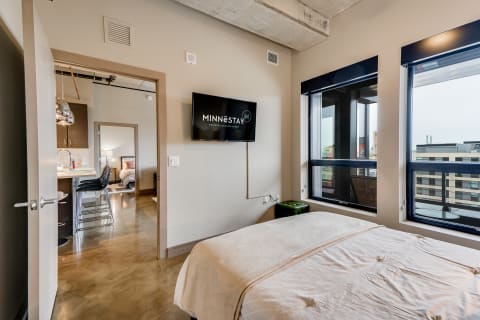 Interior view of a modern vacation rental room featuring a bed and kitchenette area.