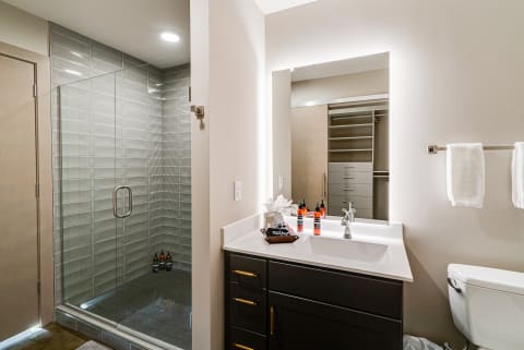 Interior view of a modern bathroom with a shower, vanity, and toilet.