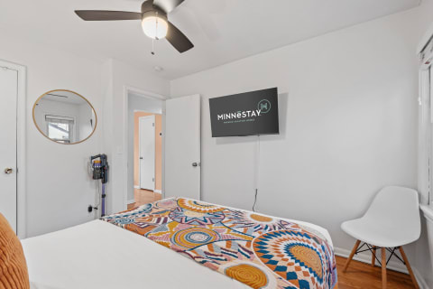 Cozy bedroom with colorful throw blanket, flat-screen TV, and stylish furniture.