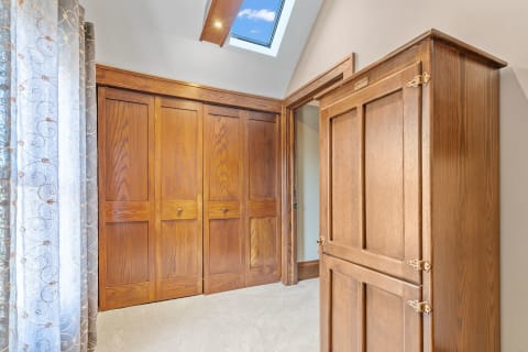 Interior corner of a room showing a wooden wardrobe and light curtains.