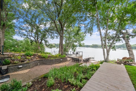Serene lakeside view featuring a winding brick pathway and comfortable seating area.