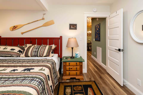 Cozy bedroom featuring a red bed frame, bear-patterned quilt, and rustic decor.