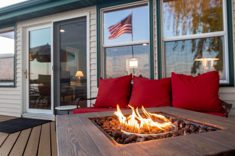 Outdoor living space with a fire pit, red cushions, and a view of an American flag.