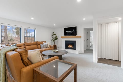 Contemporary living room with leather sofa, fireplace, and large windows.