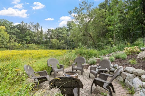 Outdoor patio with chairs and fire pit in a green landscape.